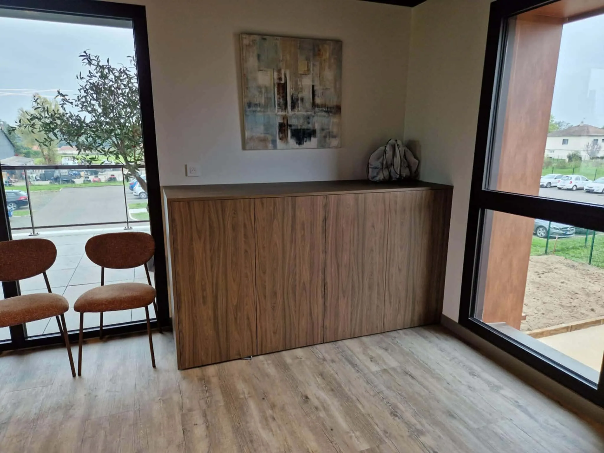 Meuble bas en bois sous une grande fenêtre, avec deux chaises