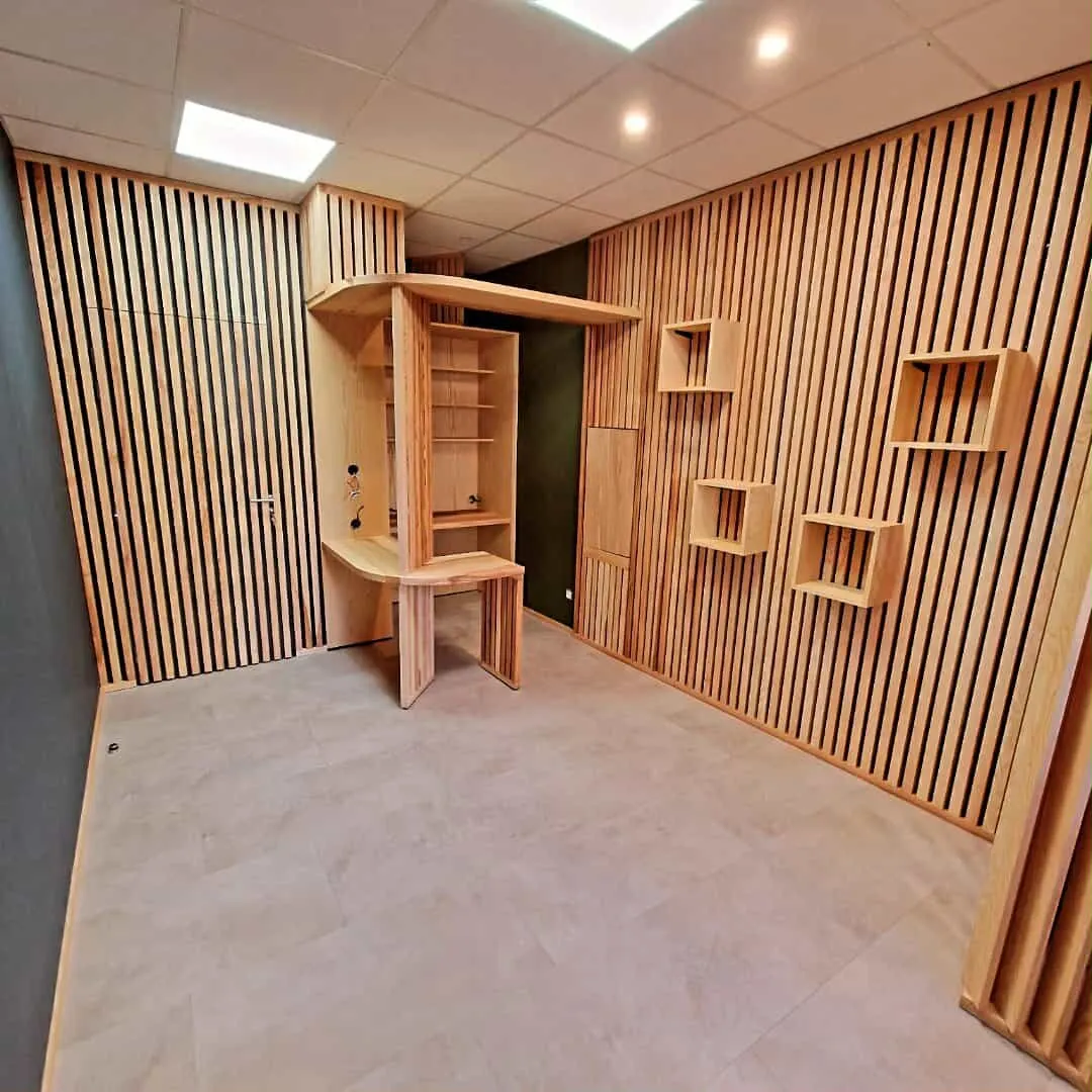 Local commercial habillé de tasseaux de bois, avec niches de présentation carrées fixées au mur et comptoir en bois